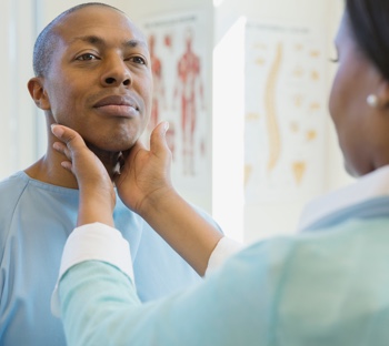female doctor examining male patient's glands in clinic