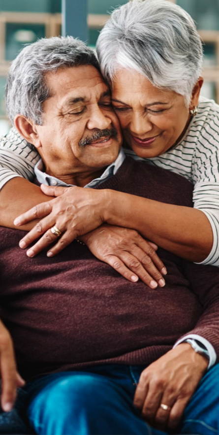 wife wrapping her arms around her sitting husband