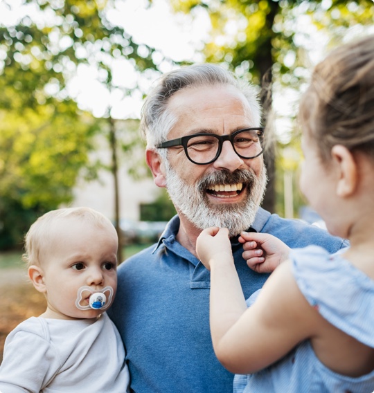 grandfather holding grandchildren and smiling